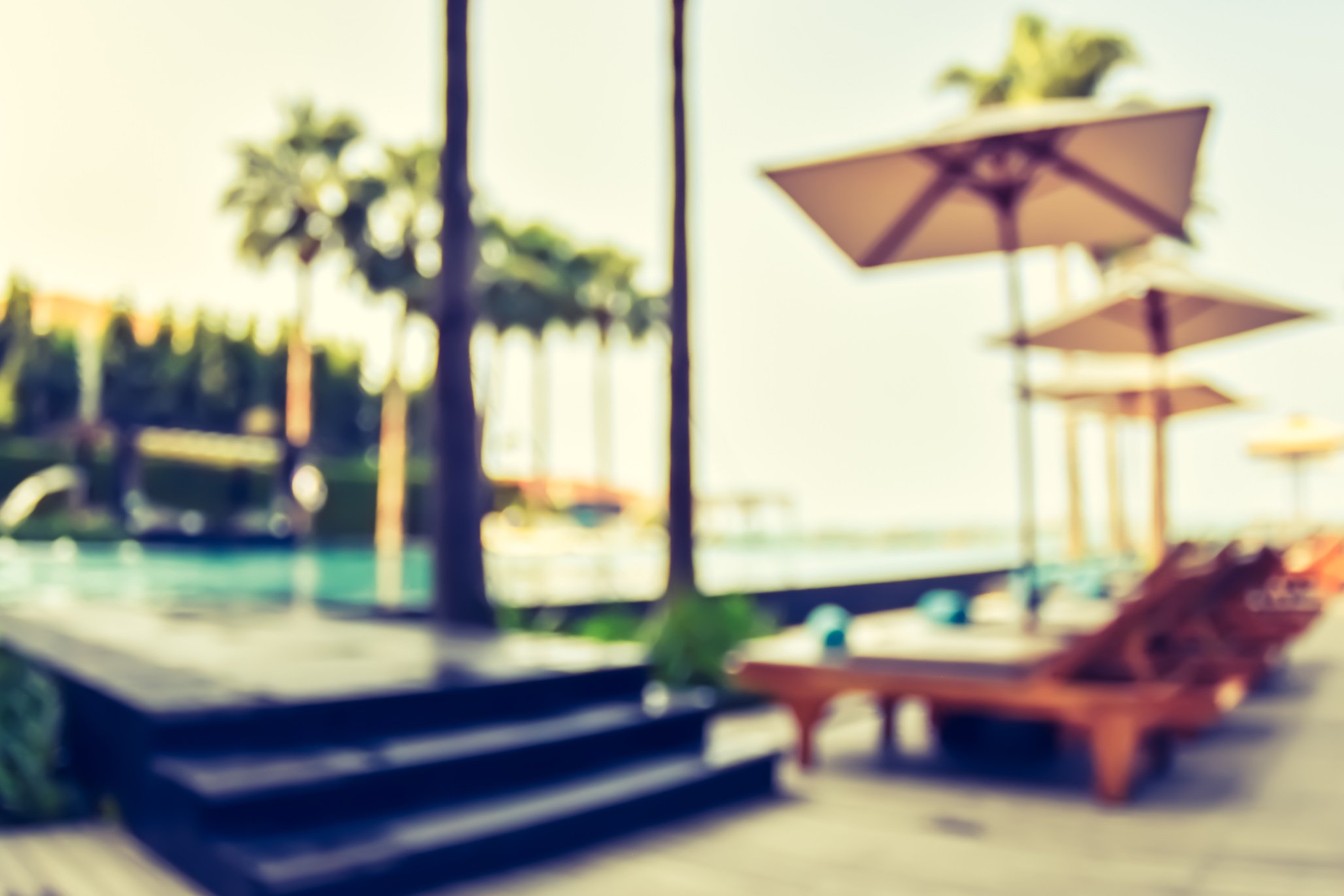 Blur summer background poolside party with blurry tropical resort hotel swimming pool place